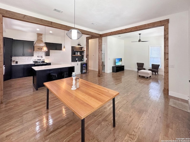 kitchen featuring pendant lighting, electric range, a center island, tasteful backsplash, and custom exhaust hood