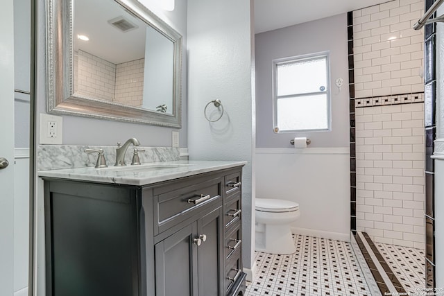 bathroom featuring vanity, toilet, and tiled shower