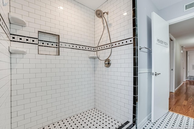 bathroom with tiled shower and hardwood / wood-style floors