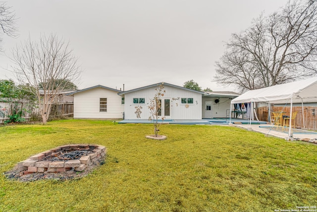 rear view of property with a patio area, a lawn, an outdoor structure, a fenced in pool, and a fire pit