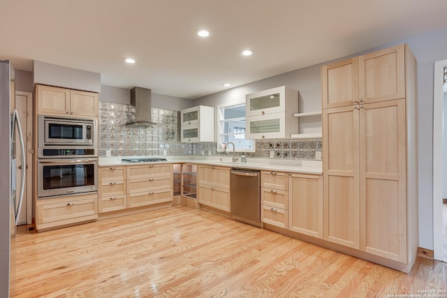 kitchen featuring light brown cabinetry, wall chimney range hood, and stainless steel appliances