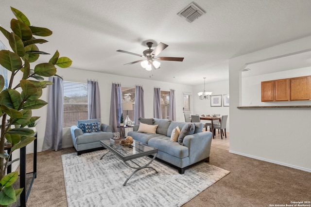 carpeted living room with ceiling fan with notable chandelier and a textured ceiling