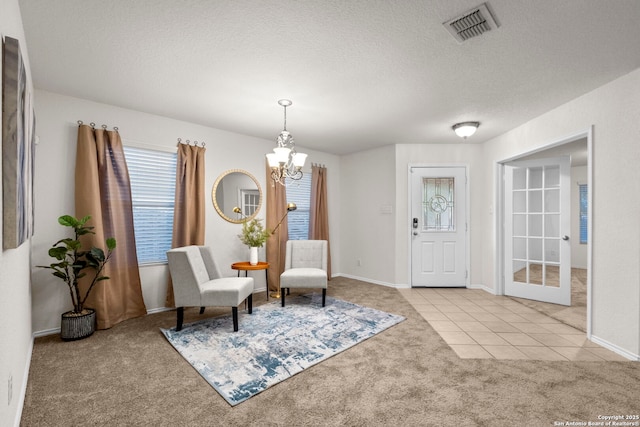 living area featuring light carpet, a textured ceiling, and an inviting chandelier