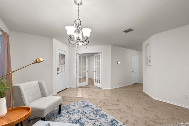 living area with light tile patterned flooring, a chandelier, and french doors