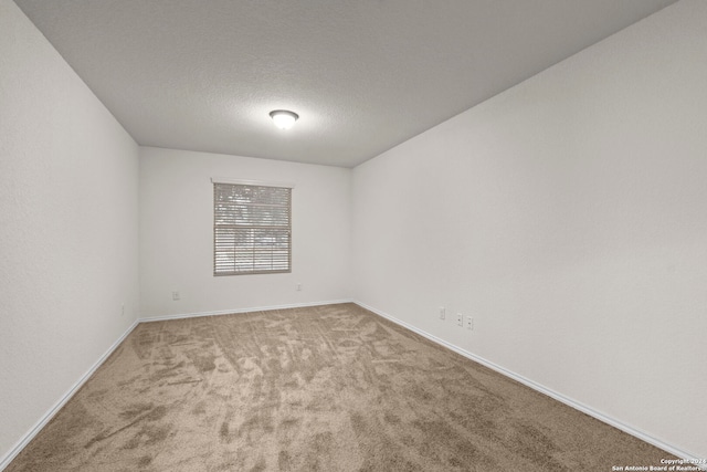 empty room with light carpet and a textured ceiling