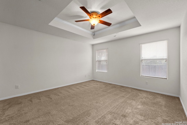 spare room with ceiling fan, light colored carpet, ornamental molding, and a tray ceiling