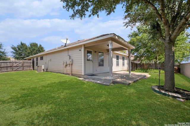 rear view of house with central AC, a patio, and a lawn