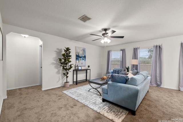 living room with a textured ceiling, light colored carpet, and ceiling fan