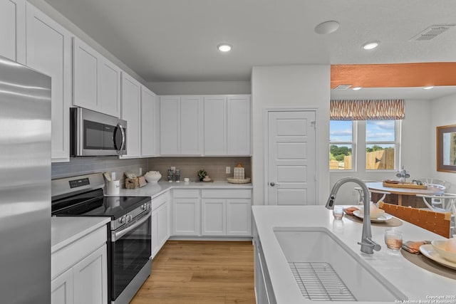 kitchen with white cabinetry, stainless steel appliances, sink, and decorative backsplash