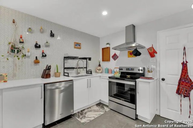 kitchen featuring wall chimney exhaust hood, stainless steel appliances, sink, and white cabinets