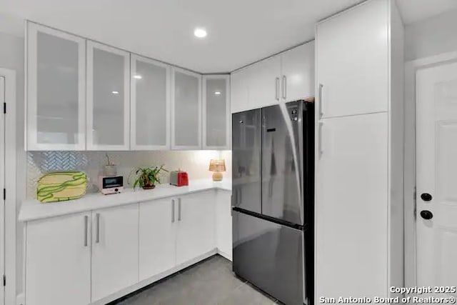 kitchen featuring white cabinetry, stainless steel fridge, and backsplash