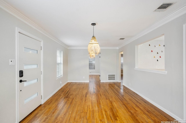 interior space with a notable chandelier, crown molding, and light wood-type flooring