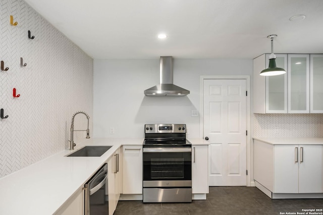 kitchen with wall chimney exhaust hood, sink, decorative light fixtures, stainless steel appliances, and white cabinets