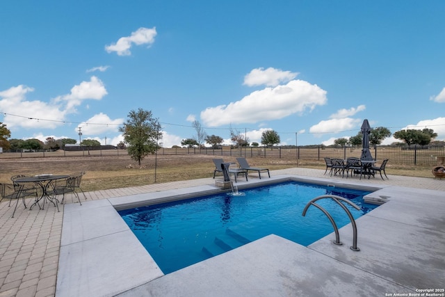 view of swimming pool with a patio and a rural view