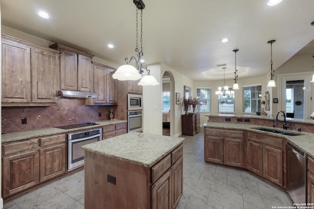 kitchen with pendant lighting, sink, stainless steel appliances, tasteful backsplash, and a kitchen island