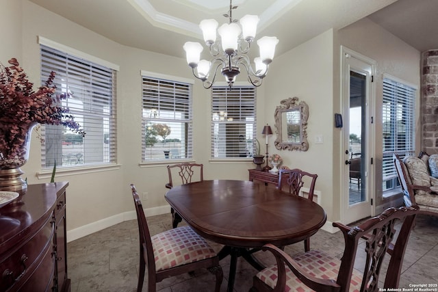 dining space featuring an inviting chandelier, plenty of natural light, crown molding, and a raised ceiling