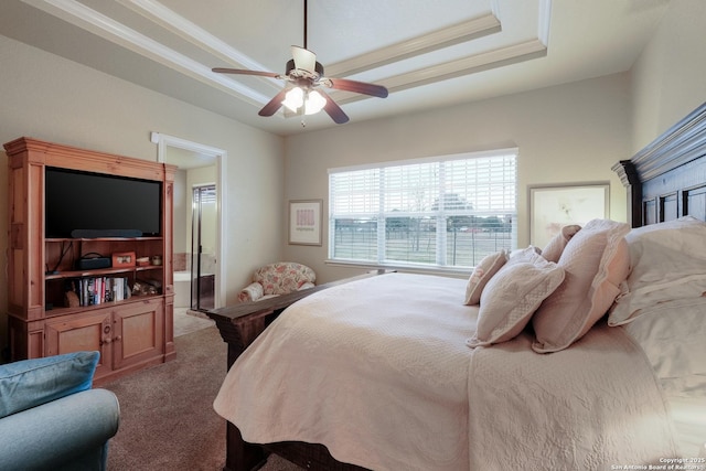 bedroom featuring a raised ceiling, carpet flooring, ceiling fan, and ensuite bath