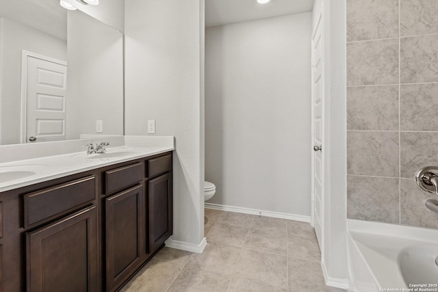 bathroom featuring double vanity, toilet, a sink, baseboards, and tile patterned floors