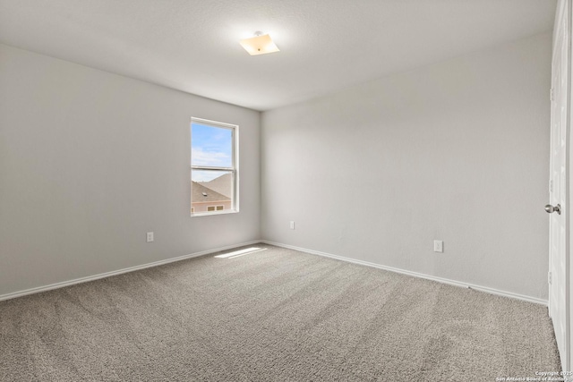 carpeted empty room featuring baseboards