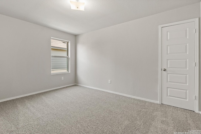 spare room featuring a textured ceiling, carpet flooring, and baseboards