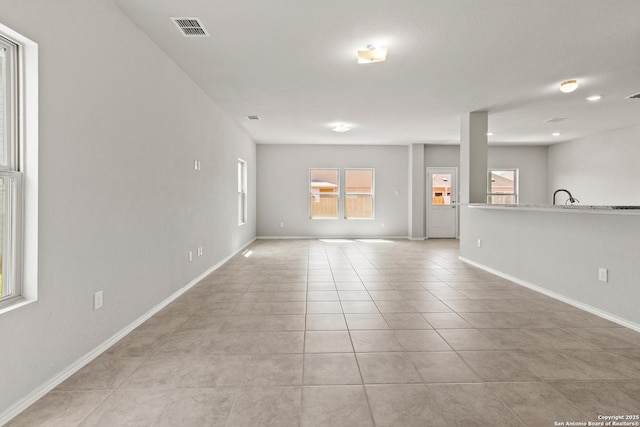 empty room with visible vents, a sink, baseboards, and light tile patterned floors