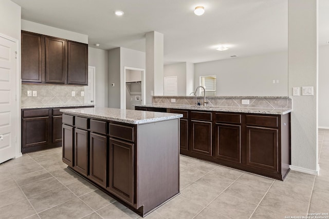 kitchen with a sink, backsplash, and dark brown cabinets