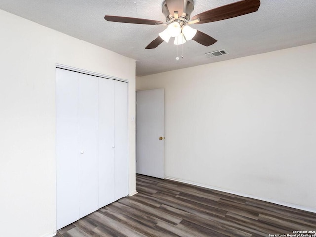 unfurnished bedroom with ceiling fan, dark hardwood / wood-style flooring, a closet, and a textured ceiling