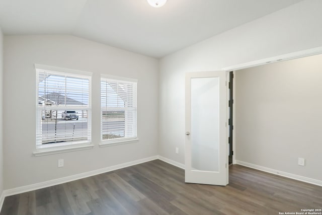 unfurnished bedroom featuring wood finished floors, baseboards, and vaulted ceiling