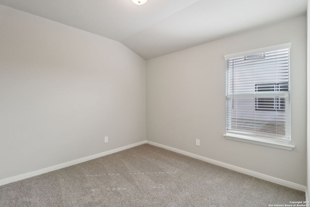 carpeted empty room featuring lofted ceiling and baseboards