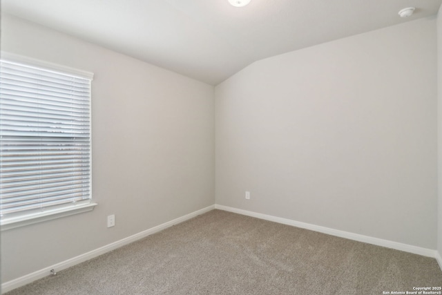 carpeted empty room featuring lofted ceiling and baseboards