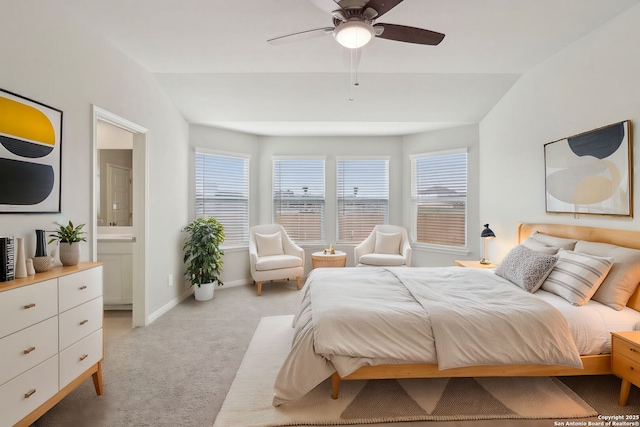 bedroom featuring vaulted ceiling, light colored carpet, baseboards, and ensuite bathroom