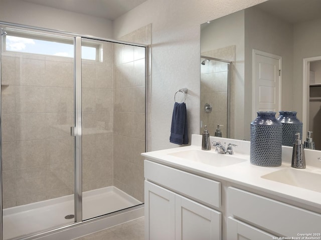 full bath with double vanity, a shower stall, and a sink