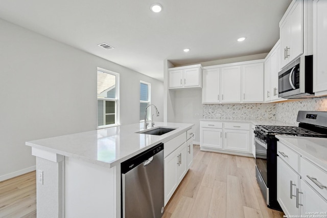 kitchen with light wood-style flooring, a sink, tasteful backsplash, visible vents, and appliances with stainless steel finishes