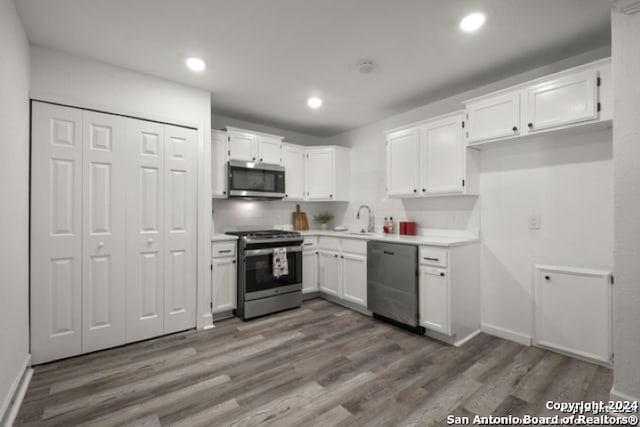 kitchen featuring dark wood-type flooring, sink, white cabinetry, stainless steel appliances, and decorative backsplash