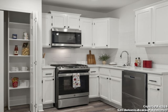 kitchen featuring dark hardwood / wood-style floors, tasteful backsplash, white cabinetry, sink, and stainless steel appliances