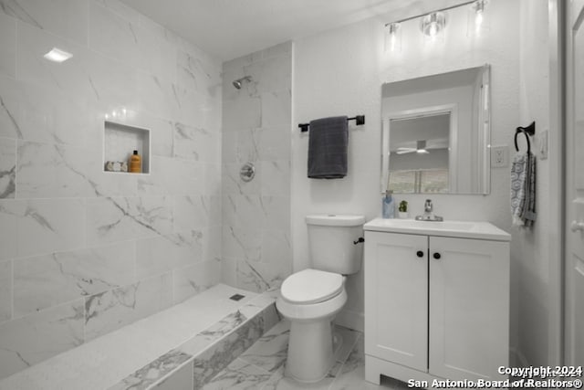 bathroom with vanity, toilet, and a tile shower