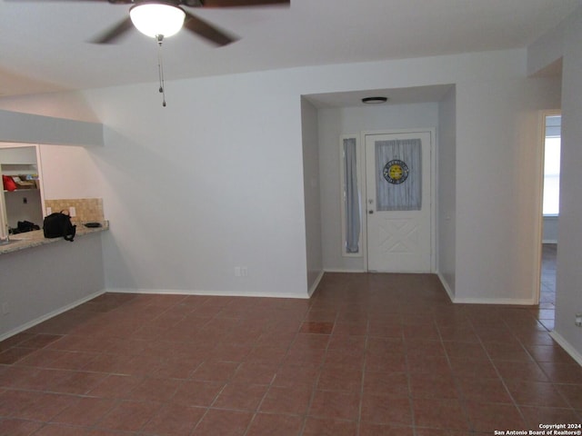 spare room featuring ceiling fan and dark tile patterned floors