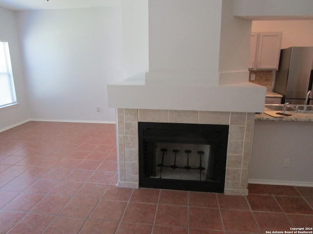 room details featuring a tiled fireplace, stainless steel fridge, and tasteful backsplash