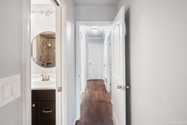 corridor with crown molding, sink, and dark wood-type flooring