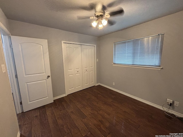 unfurnished bedroom with a textured ceiling, dark wood-type flooring, a closet, and ceiling fan