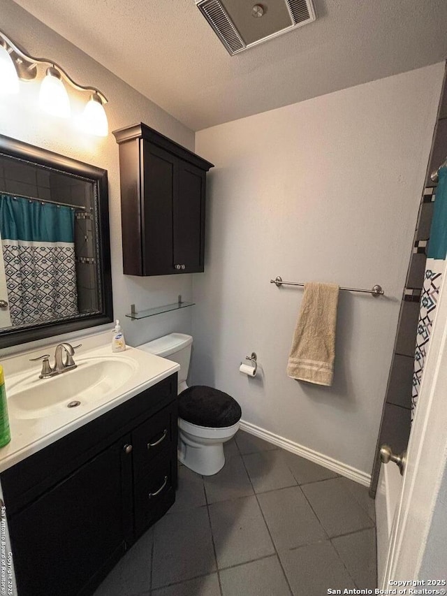 bathroom featuring tile patterned flooring, vanity, a textured ceiling, and toilet