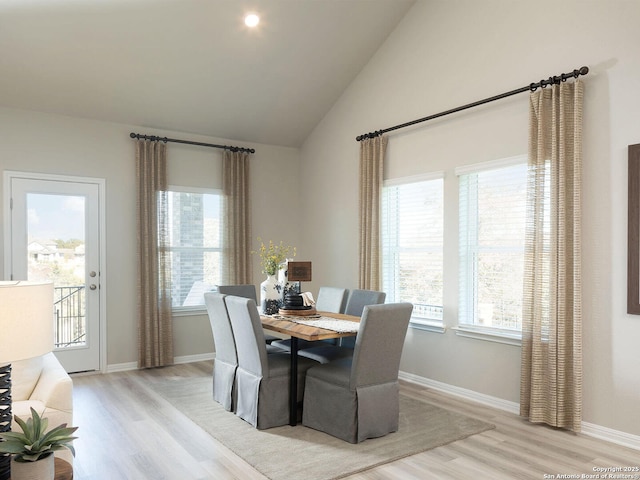 dining area featuring a healthy amount of sunlight, vaulted ceiling, and light hardwood / wood-style flooring