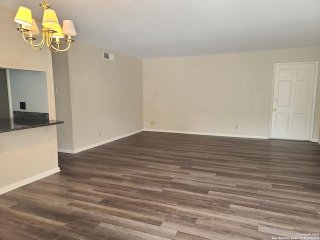 unfurnished living room featuring dark hardwood / wood-style floors and a chandelier