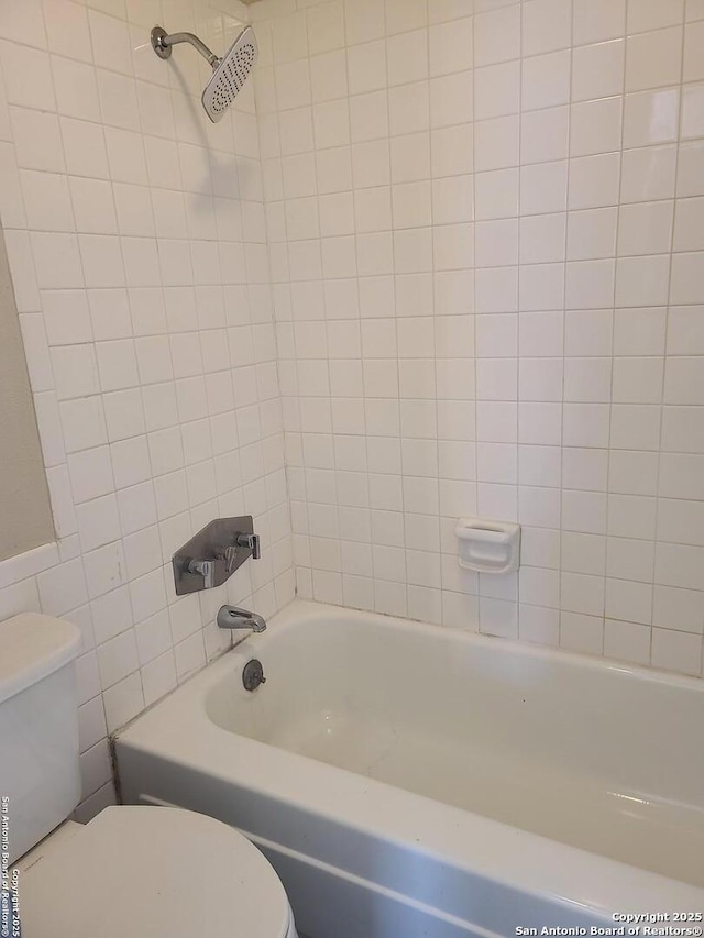 bathroom featuring tiled shower / bath combo and toilet