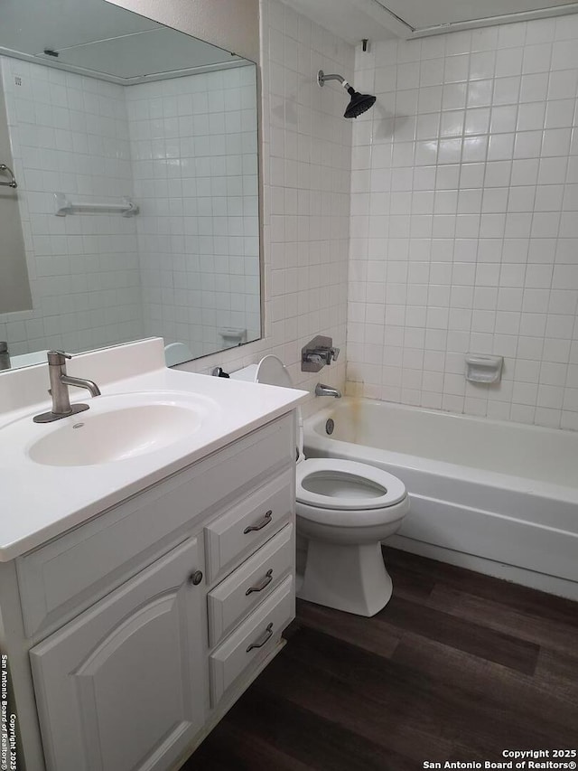 full bathroom featuring hardwood / wood-style flooring, vanity, toilet, and tiled shower / bath combo