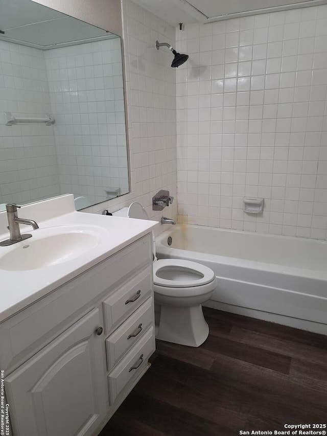 full bathroom featuring wood-type flooring, toilet, vanity, and tiled shower / bath