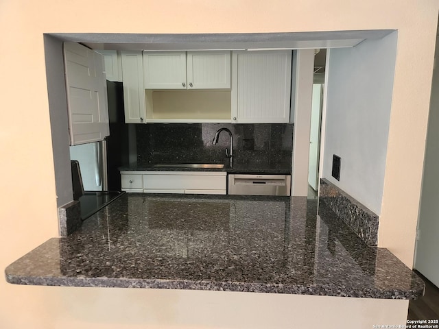 kitchen featuring white cabinetry, sink, backsplash, dark stone counters, and stainless steel dishwasher