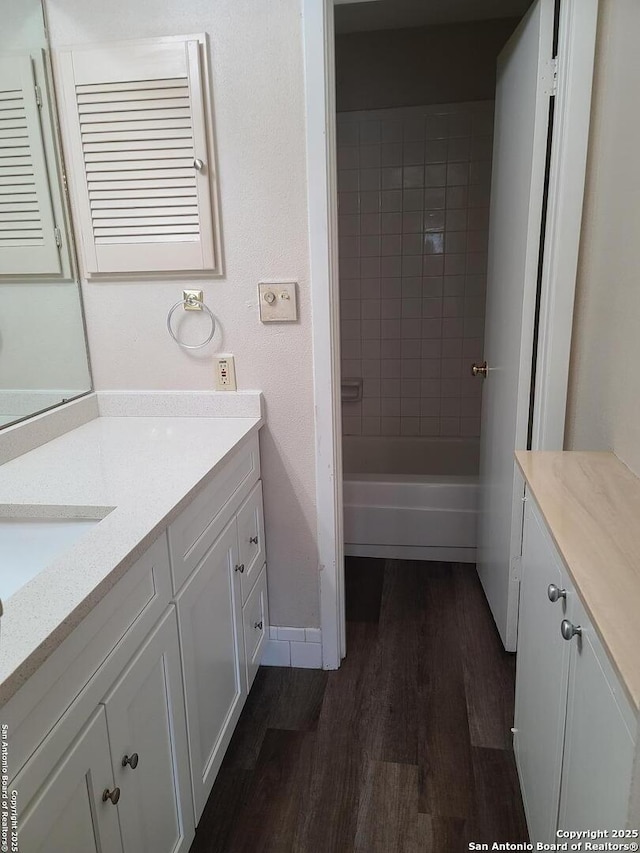 bathroom with vanity, tiled shower / bath combo, and wood-type flooring