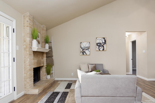 living room featuring a brick fireplace, wood-type flooring, and vaulted ceiling