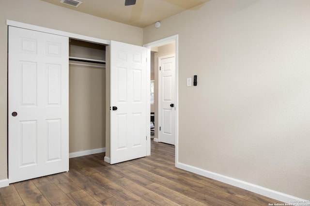 unfurnished bedroom featuring dark hardwood / wood-style floors, ceiling fan, and a closet